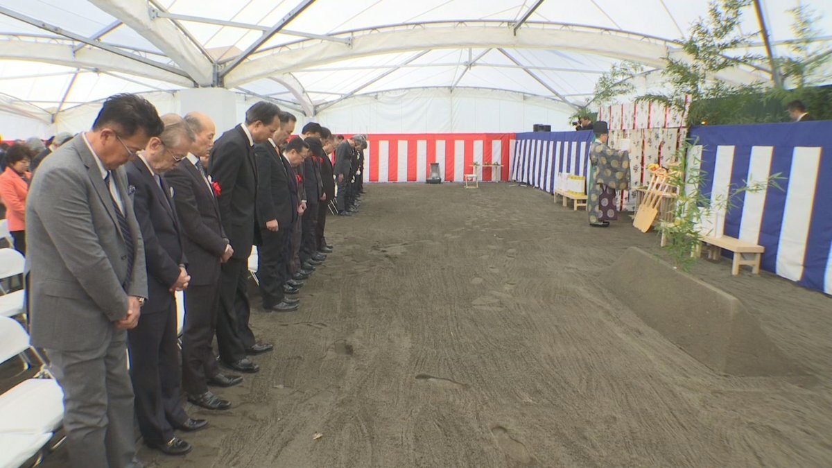 更地のテント内で参列者が頭を下げている風景